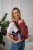 Modelka nosi dziecko w ergonomicznego nosidle KAVKA Multi‑Age burgundy braid cotton - burgundowe nosidło z białym wzorem warkocza
