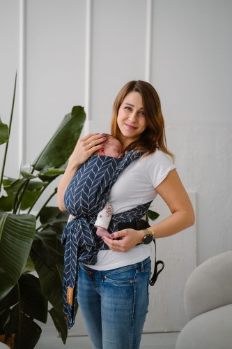 Modelka nosi dziecko w wiązanym ergonomicznym nosidle KAVKA handy ink braid cotton - granatowe nosidło z białym wzorem warkocza (ink braid cotton with white braid pattern)