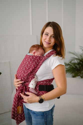 Modelka nosi dziecko w ergonomicznego nosidle KAVKA handy burgundy braid cotton - burgundowe nosidło z białym wzorem warkocza (burgundy carrier with a white braid pattern)