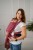 Modelka nosi dziecko w ergonomicznego nosidle KAVKA handy burgundy braid cotton - burgundowe nosidło z białym wzorem warkocza (burgundy carrier with a white braid pattern)