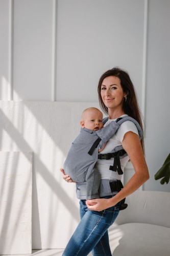 Modelka nosi dziecko w ergonomicznym nosidle KAVKA multi-age ink twill -  niebieskie nosidło z delikatnym wzorem w jodełkę. (a blue carrier with a twill - delicate herringbone pattern.)