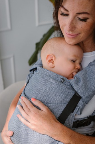 Modelka nosi dziecko w ergonomicznym nosidle KAVKA multi-age ink twill -  niebieskie nosidło z delikatnym wzorem w jodełkę. (a blue carrier with a twill - delicate herringbone pattern.)