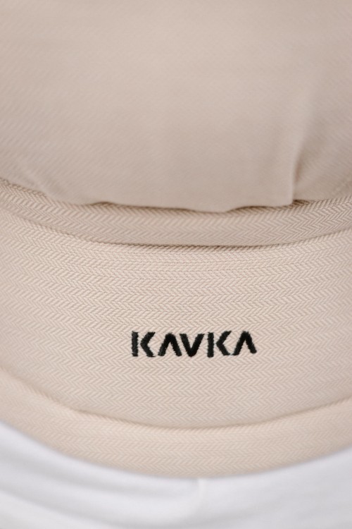Modelka nosi dziecko w ergonomicznym nosidle KAVKA multi-age vanilla twill  - beżowe nosidło z białym wzorem w drobną jodełkę.   (a beige carrier with a white twill pattern)