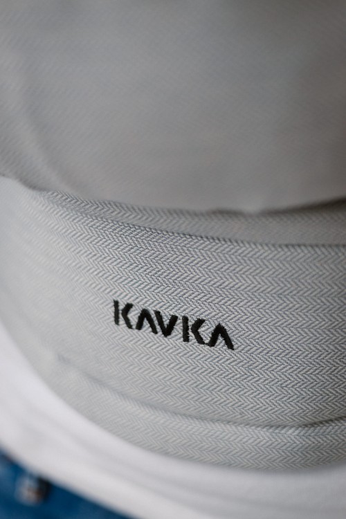 Modelka nosi dziecko w ergonomicznym nosidle KAVKA multi-age PLUS verona twill - szare nosidło z białym  wzorem w drobną jodełkę  (a grey baby carrier with subtele white twill pattern)