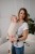 Modelka nosi dziecko w ergonomicznym nosidle KAVKA handy vanilla twill -  beżowe nosidło z białym  wzorem w drobną jodełkę  (a beige baby carrier with white twill  pattern)